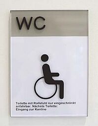 Beschilderung barrierefreier Toilette mit ertastbarem Piktogramm und Beschriftung im Land- und Amtsgericht Düsseldorf