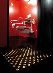 Kontrastierend gestaltete barrierefreie Toilette (rote Wände, weiße Sanitärgegenstände, schwarzer Fußboden und schwarze Rückenlehne) mit Anbindung an das Bodenleitsystem, Staatstheater Darmstadt